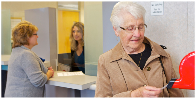 Salle d'attente de la CLI : une femme prend un numéro dans un distributeur. En arrière-plan, une autre femme obtient des services au guichet.